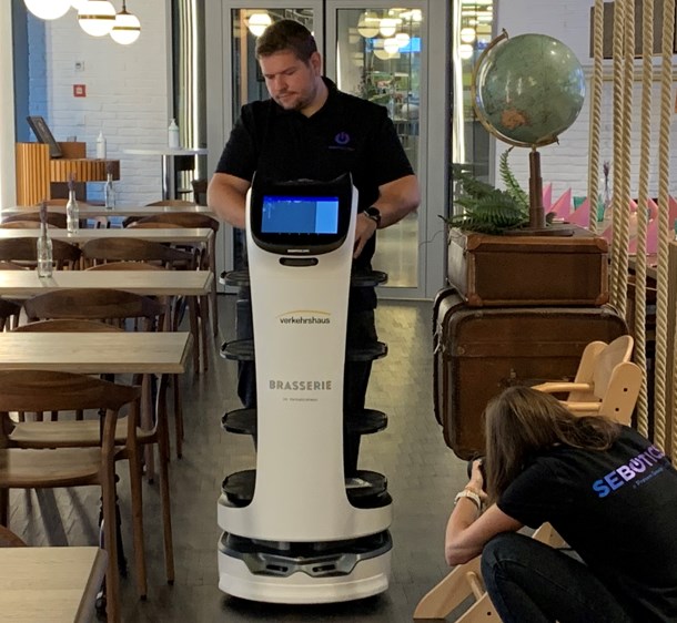 A Sebotics employee scans the room of a restaurant with Bellabot